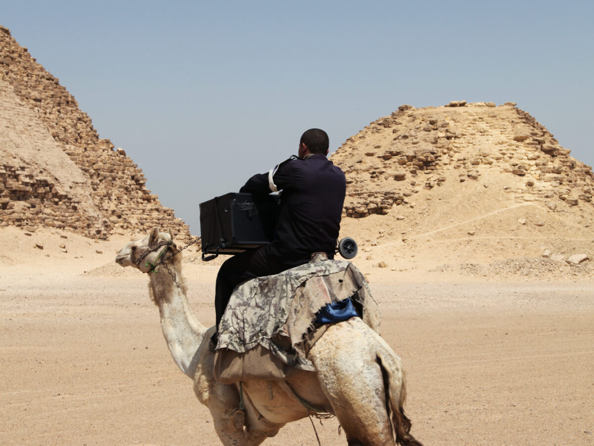 Egypt, Bent Pyramid, Guard Carries Suitcase Camera on Camel